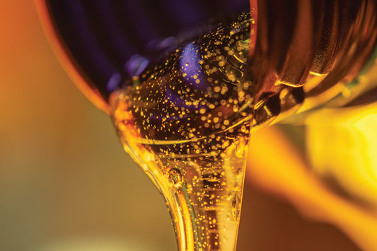 Oil pouring out of a bottle in yellow lighting.