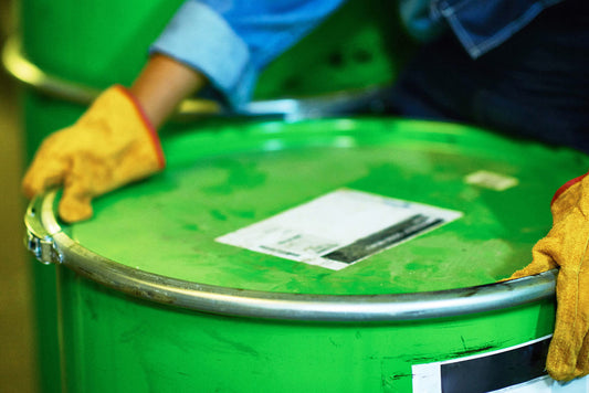 Top of oil green drum with a persons hands moving it.